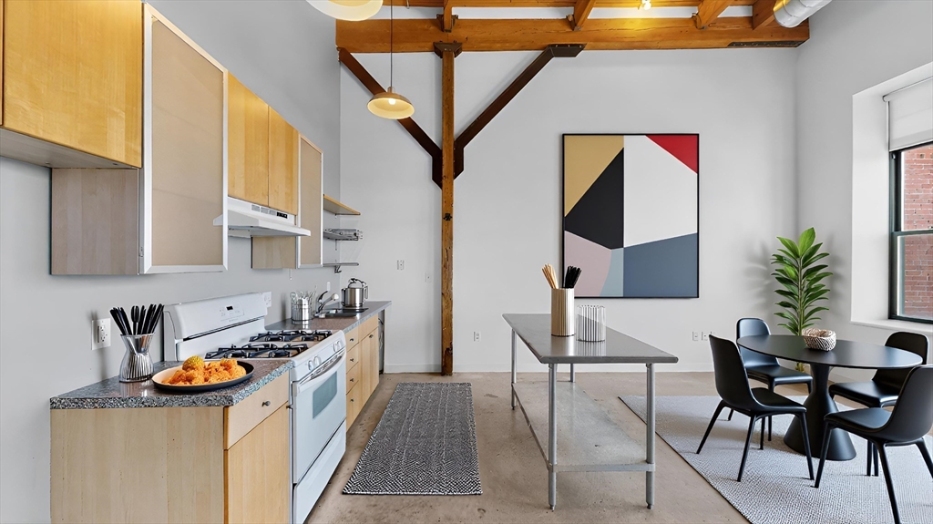 a kitchen with stainless steel appliances granite countertop a stove top oven a dining table and chairs