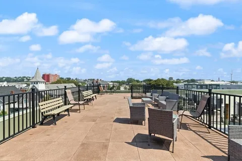 a view of a terrace with lawn chairs and iron fence
