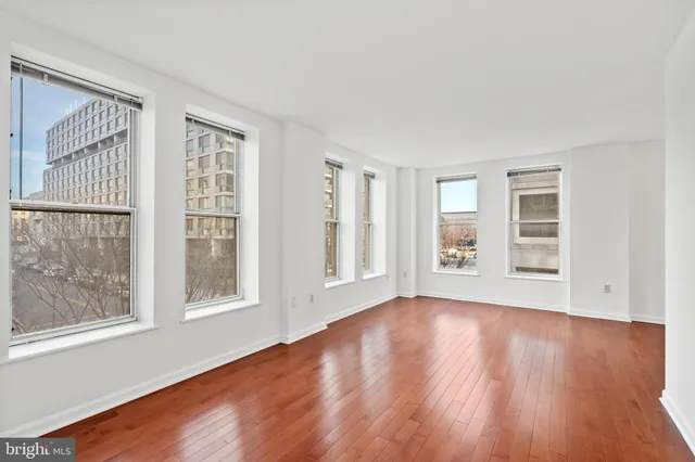 a view of an empty room with wooden floor and windows