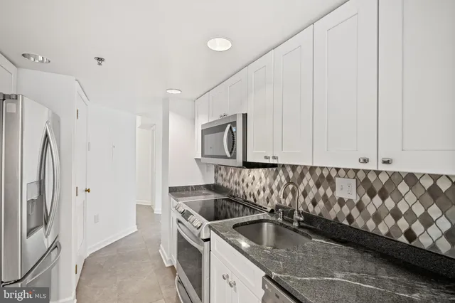 a kitchen with granite countertop a sink and a refrigerator