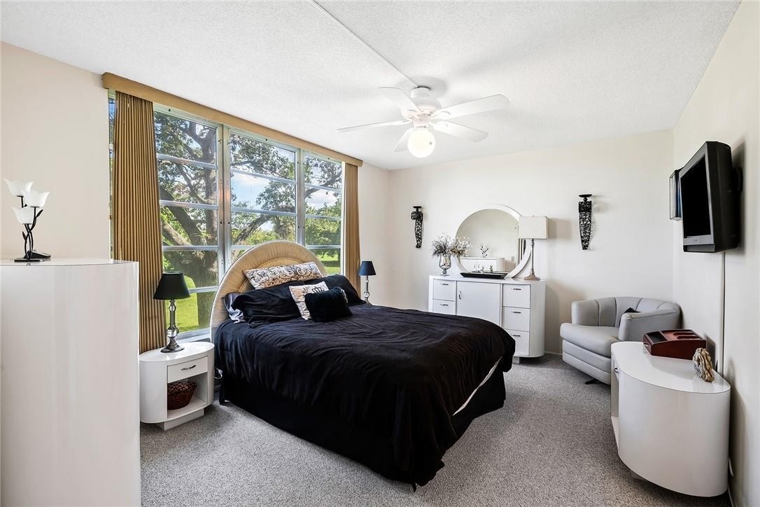 2661 South Course Drive, Unit 209 Pompano Beach, FL 33069 - Photo 13 of 21 a bedroom with a bed and a chandelier