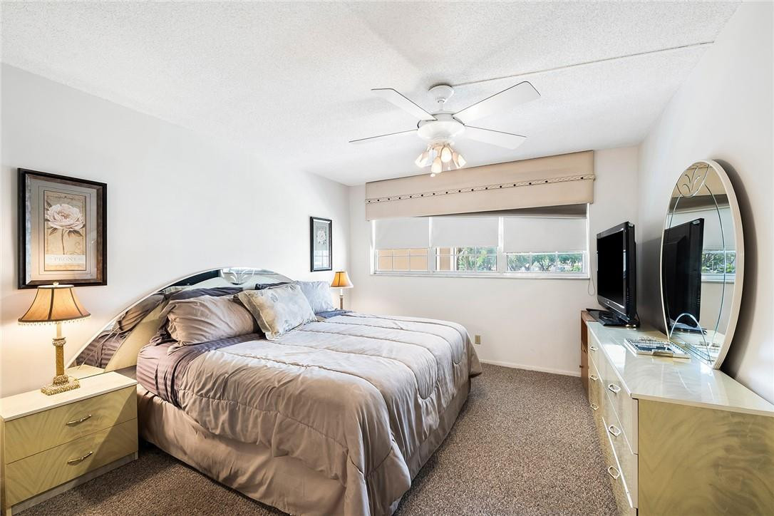 2661 South Course Drive, Unit 209 Pompano Beach, FL 33069 - Photo 16 of 21 a bedroom with a bed and a flat screen tv