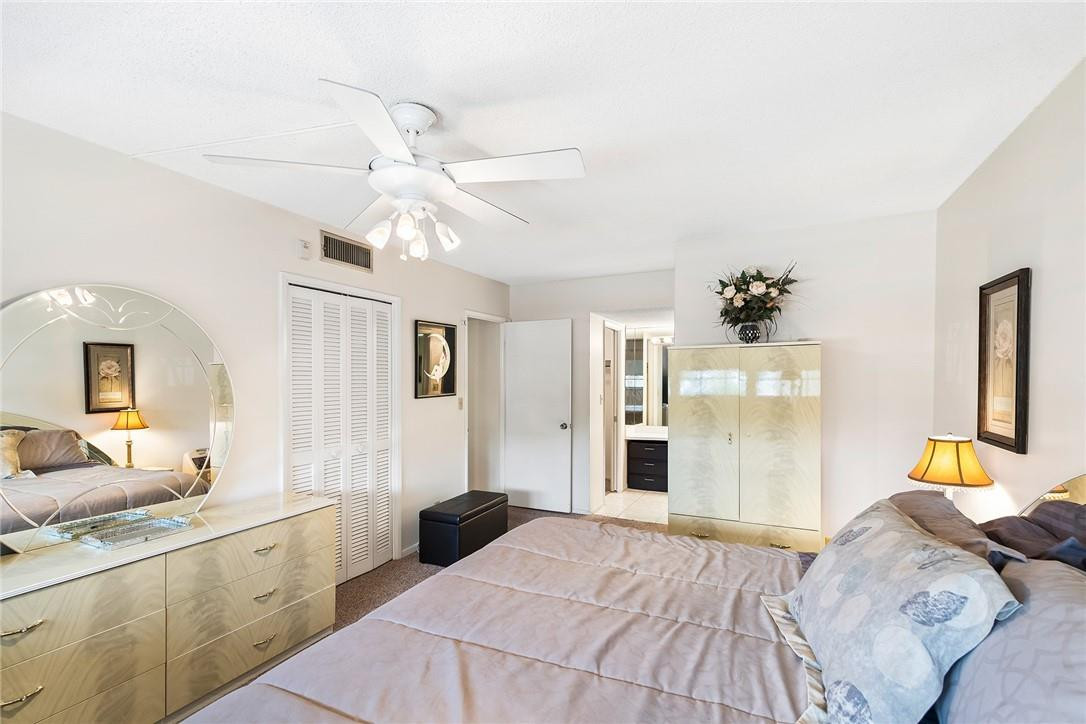 2661 South Course Drive, Unit 209 Pompano Beach, FL 33069 - Photo 17 of 21 a bedroom with a bed and a chandelier