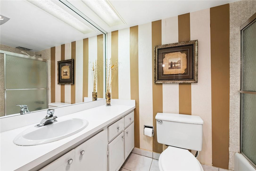 2661 South Course Drive, Unit 209 Pompano Beach, FL 33069 - Photo 20 of 21 a bathroom with a toilet a sink and a mirror