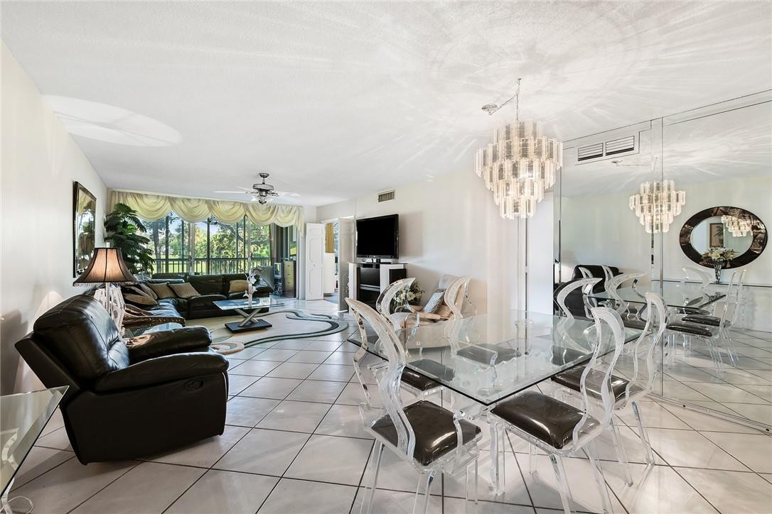 2661 South Course Drive, Unit 209 Pompano Beach, FL 33069 - Photo 7 of 21 a living room with furniture a flat screen tv and floor to ceiling window