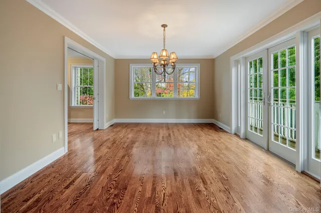 a view of a livingroom with a chandelier wooden floor and windows