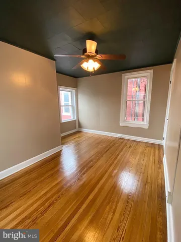 a view of empty room with wooden floor and fan