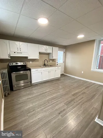a large kitchen with stainless steel appliances wooden floor and a sink