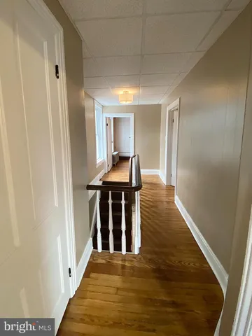 a view of a hallway with wooden floor and furniture