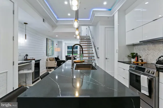 a kitchen with stainless steel appliances granite countertop a sink a stove and chairs with wooden floor