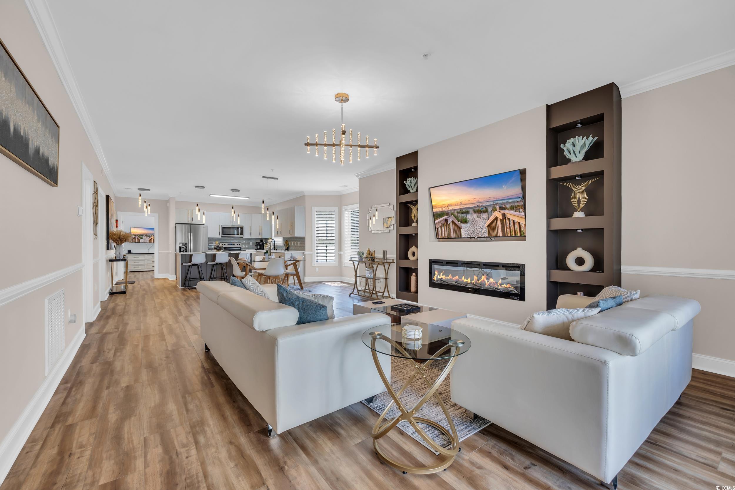 4821 Luster Leaf Circle, Unit 101 Myrtle Beach, SC 29577 - Photo 1 of 30 Living area featuring a glass covered fireplace, ornamental molding, light wood-style flooring, and a chandelier