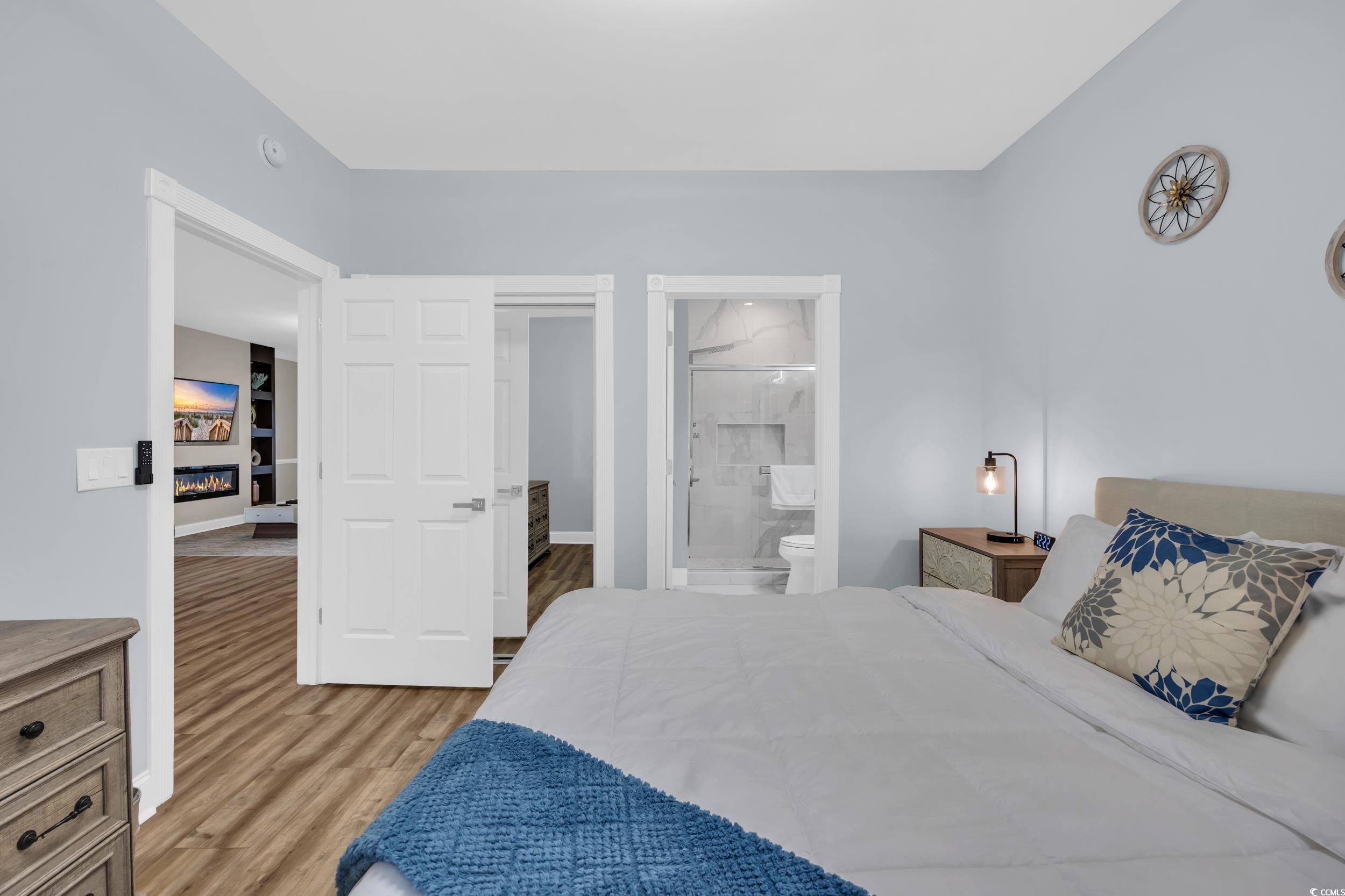 4821 Luster Leaf Circle, Unit 101 Myrtle Beach, SC 29577 - Photo 15 of 30 Bedroom featuring light wood finished floors, a glass covered fireplace, and ensuite bath