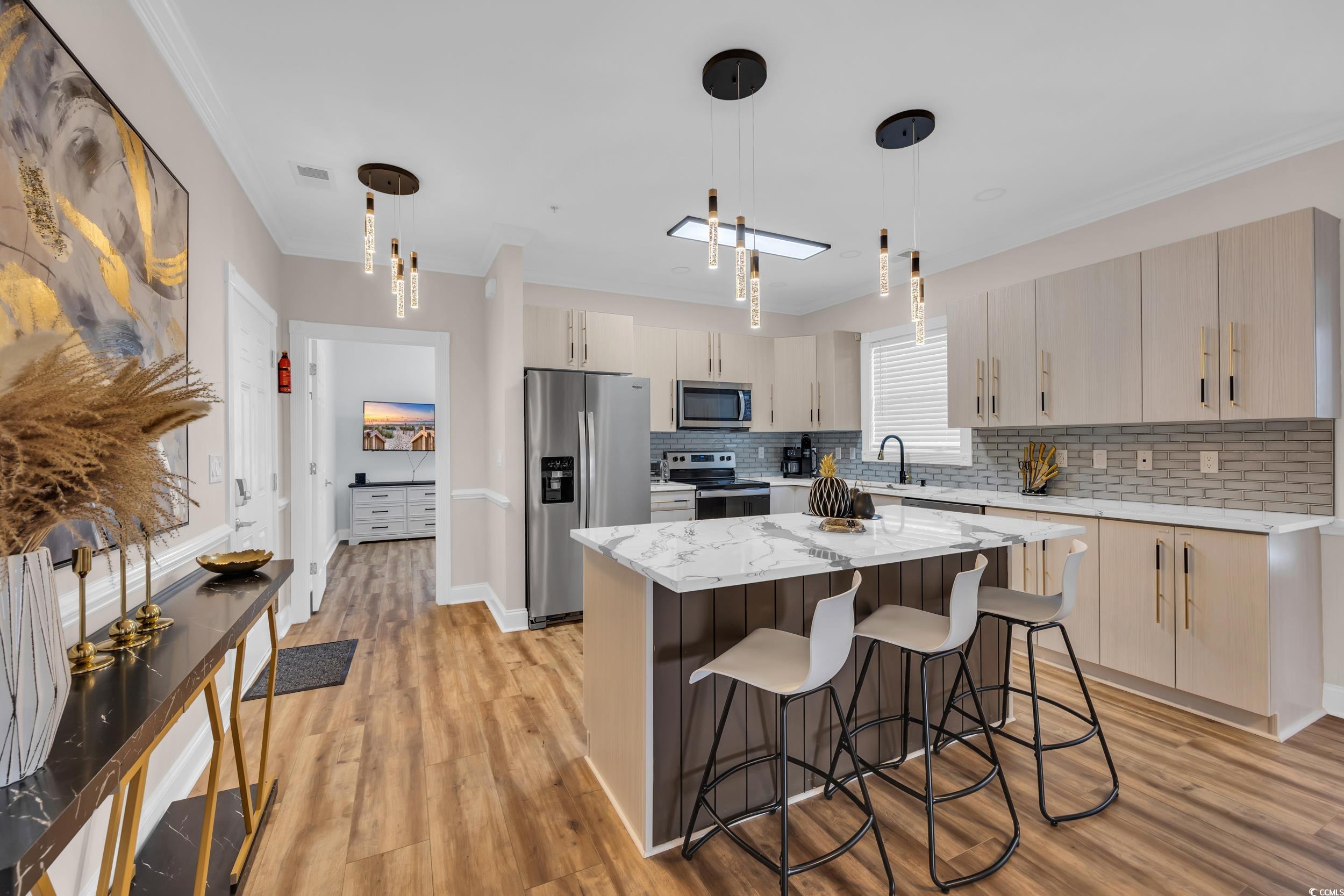4821 Luster Leaf Circle, Unit 101 Myrtle Beach, SC 29577 - Photo 17 of 30 Kitchen with a kitchen breakfast bar, light stone countertops, a kitchen island, appliances with stainless steel finishes, and decorative light fixtures