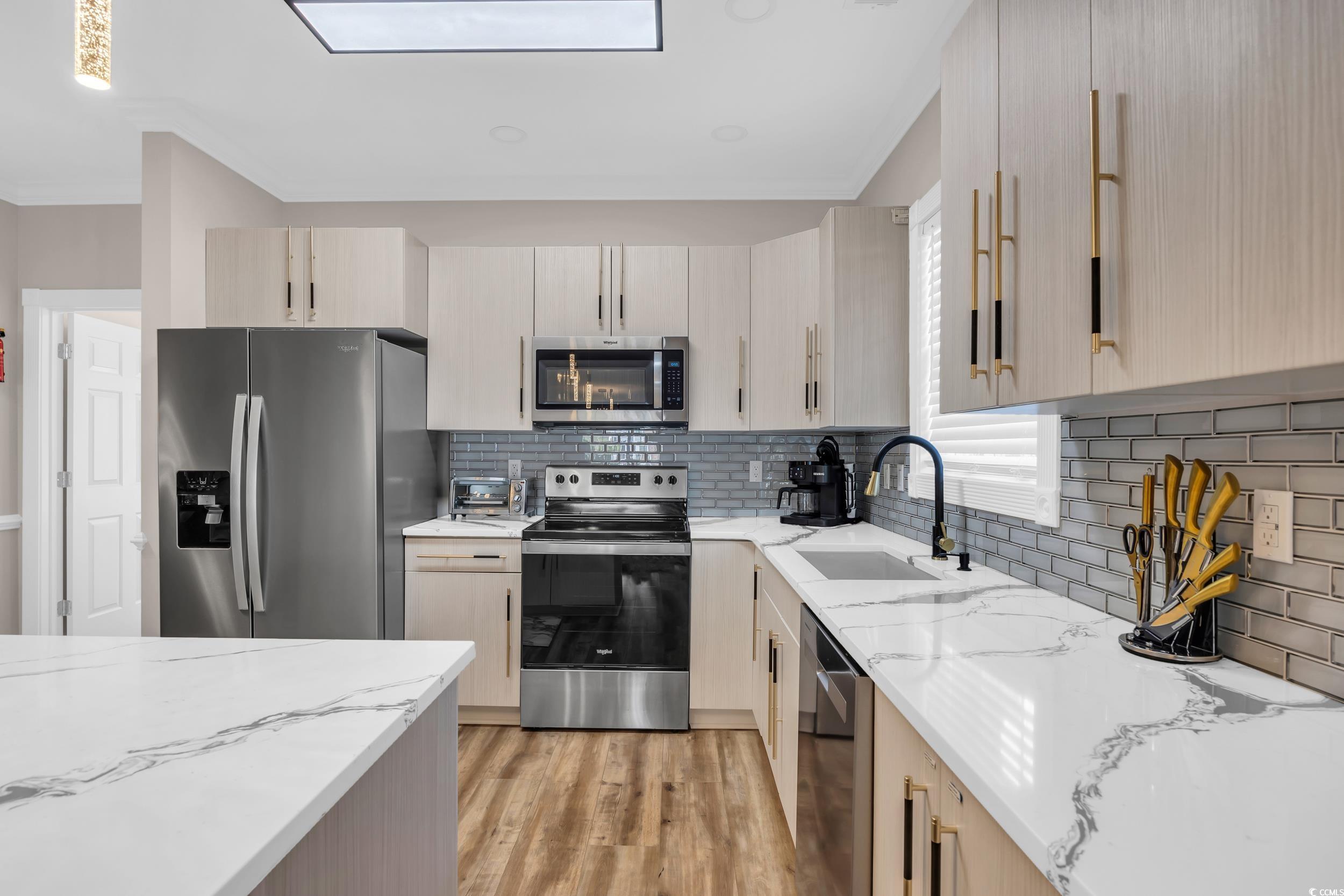4821 Luster Leaf Circle, Unit 101 Myrtle Beach, SC 29577 - Photo 18 of 30 Kitchen featuring light brown cabinets, appliances with stainless steel finishes, light stone counters, backsplash, and light wood-style flooring