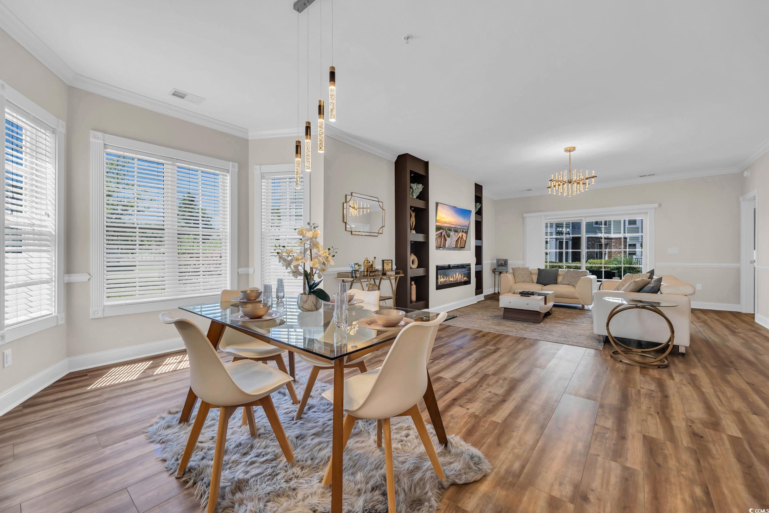 4821 Luster Leaf Circle, Unit 101 Myrtle Beach, SC 29577 - Photo 20 of 30 Dining space with ornamental molding, a glass covered fireplace, wood finished floors, and a chandelier