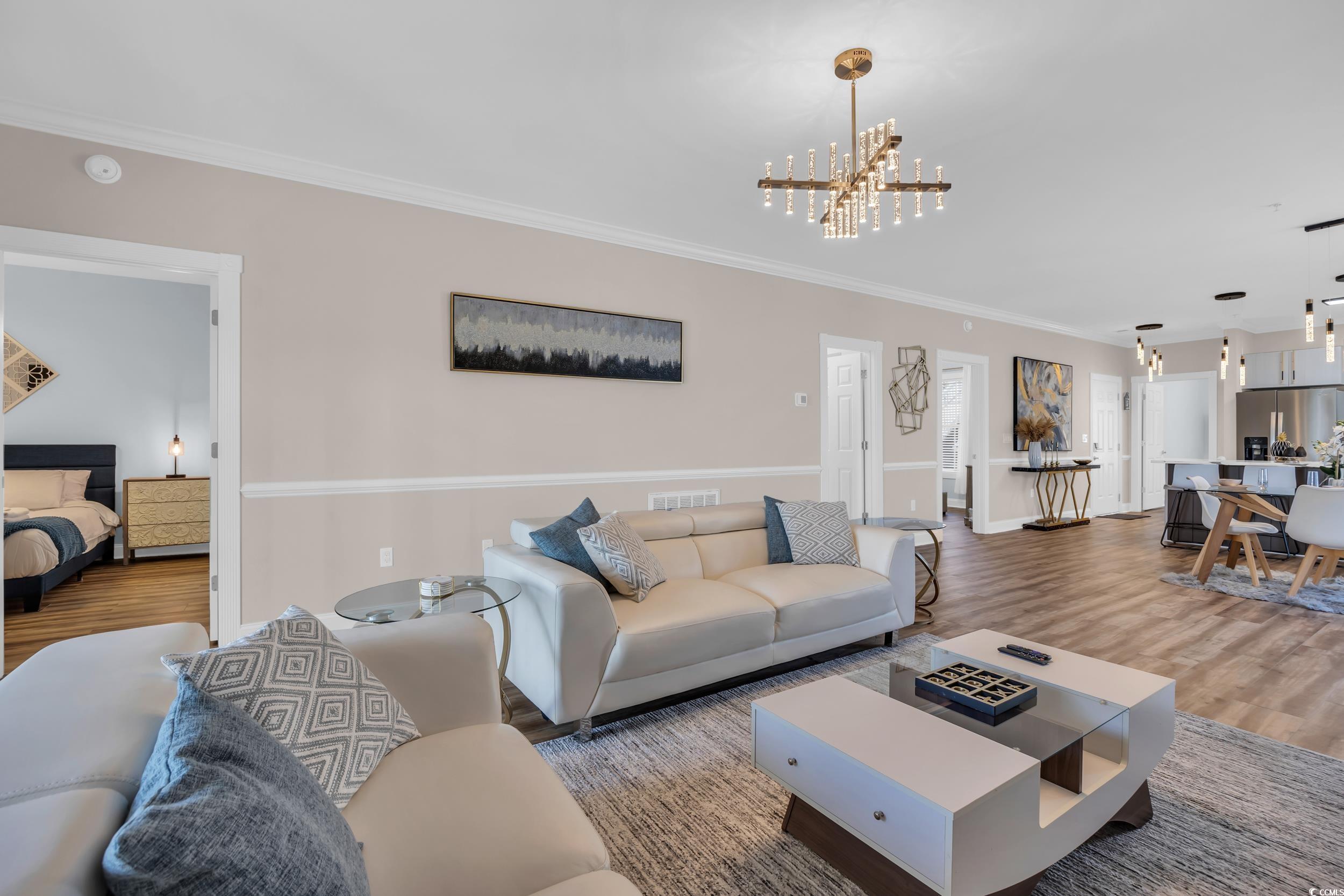 4821 Luster Leaf Circle, Unit 101 Myrtle Beach, SC 29577 - Photo 24 of 30 Living area featuring crown molding, wood finished floors, and a chandelier