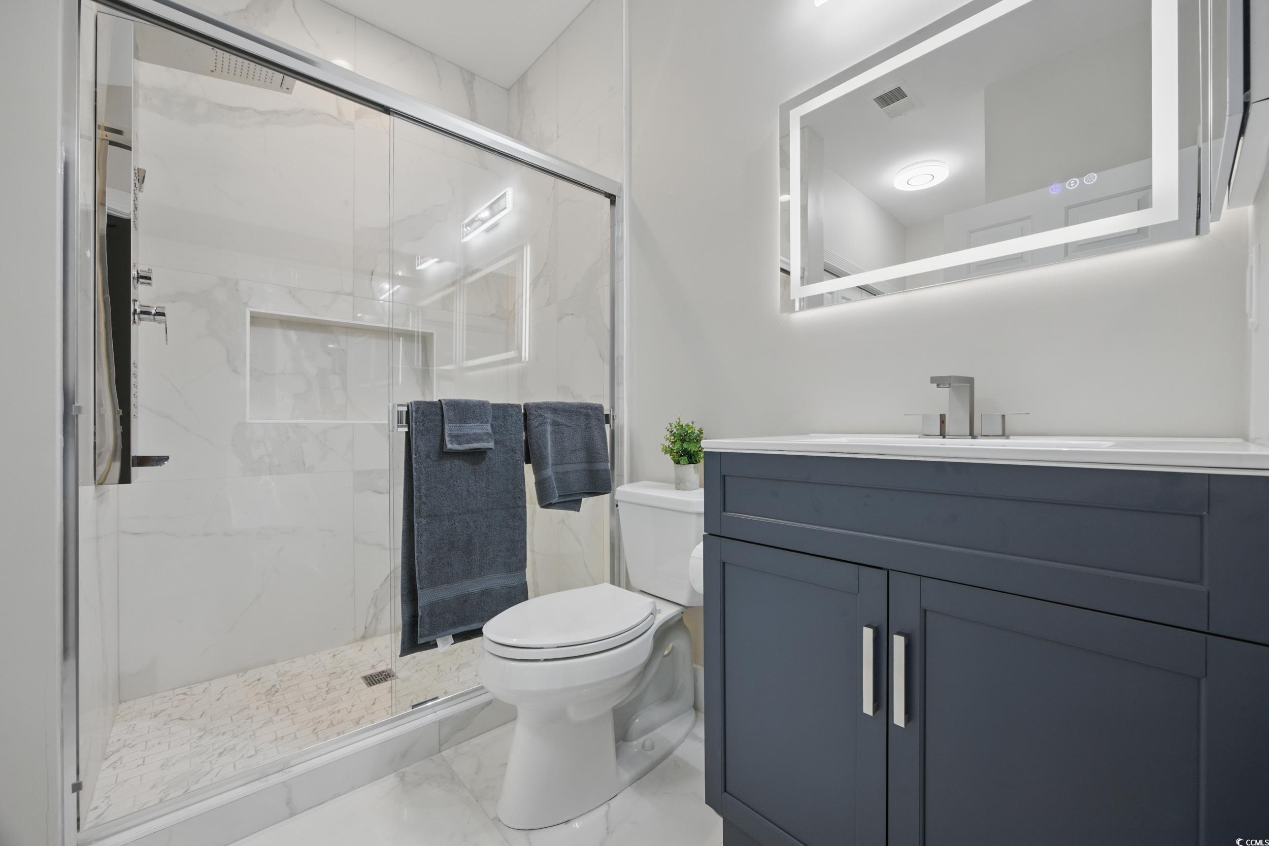 4821 Luster Leaf Circle, Unit 101 Myrtle Beach, SC 29577 - Photo 9 of 30 Bathroom with a marble finish shower, vanity, and marble look tiles