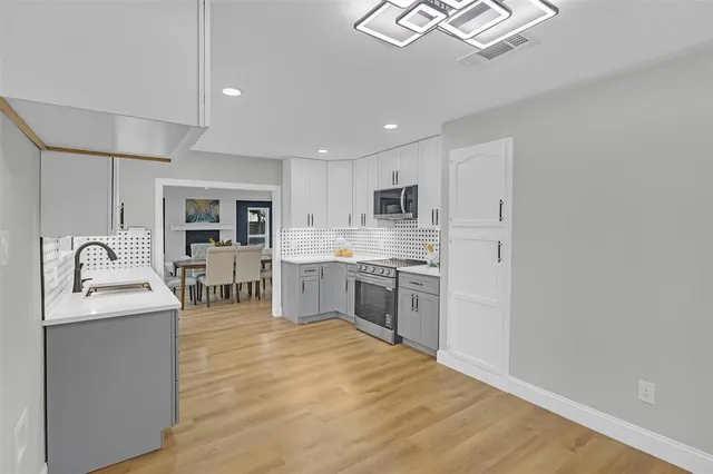 a open kitchen with stainless steel appliances granite countertop a sink cabinets and wooden floor