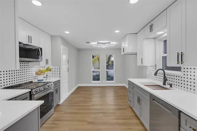 a large kitchen with stainless steel appliances a large counter top a stove and a sink