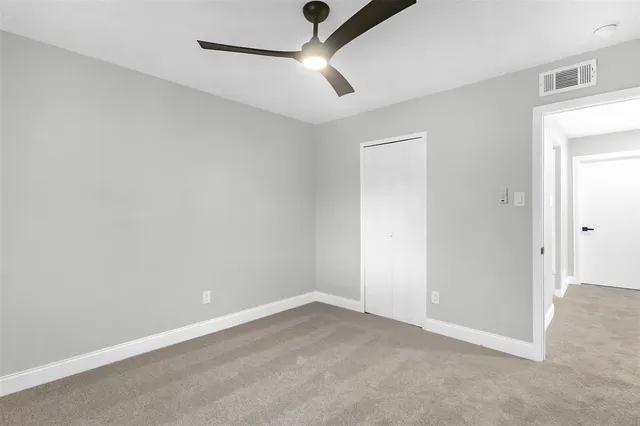 an empty room with a ceiling fan and carpet