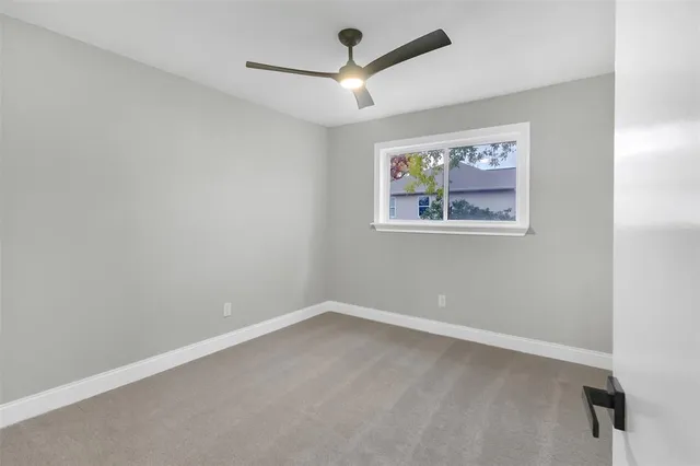 an empty room with a window and a ceiling fan