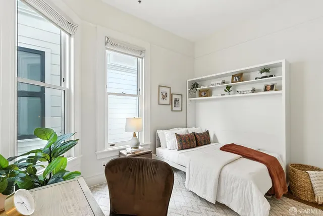 a bedroom with a bed table flowerpot and window