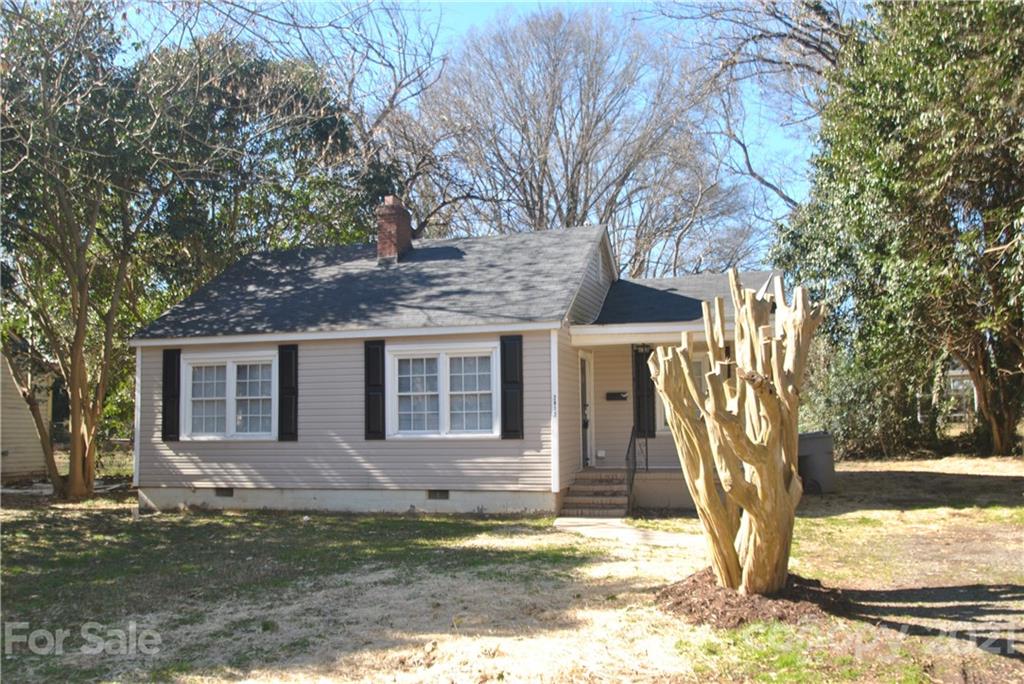 a view of a yard in front of a house with large tree