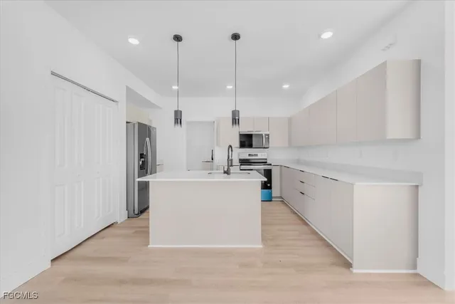 a large white kitchen with lots of counter space a sink appliances and cabinets