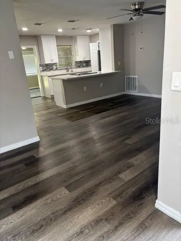 a view of kitchen with kitchen island a sink wooden floor and a counter top space