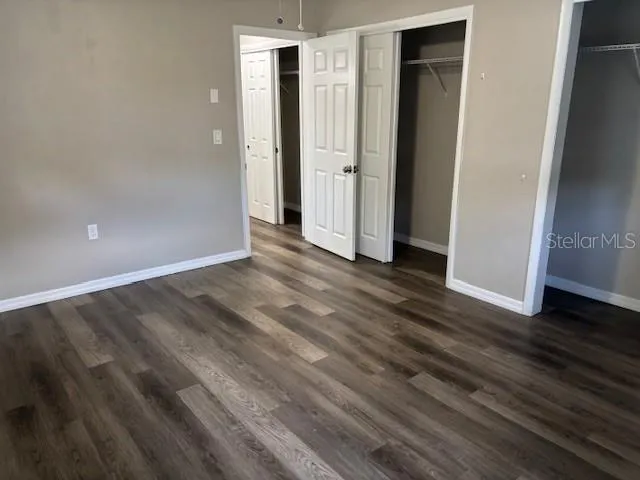 a view of an empty room with wooden floor and closet