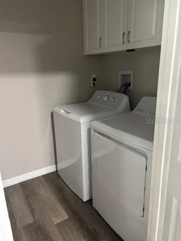 a utility room with wooden floor washer and dryer