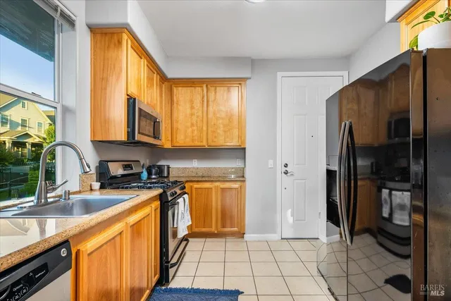 a kitchen with stainless steel appliances granite countertop a refrigerator a stove and a sink with cabinets