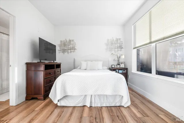 a spacious bedroom with a bed and wooden floor