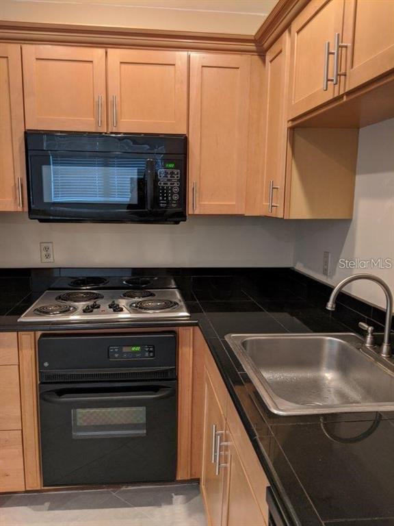 201 Bedford Trail, Unit F127 Sun City Center, FL 33573 - Photo 6 of 15 a kitchen with stainless steel appliances a sink stove and microwave