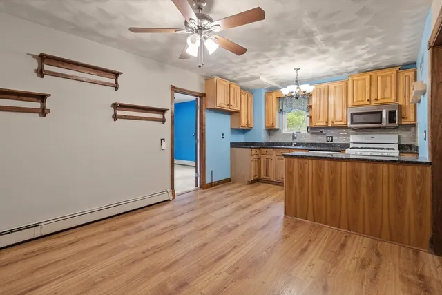 a kitchen with stainless steel appliances granite countertop a refrigerator a sink dishwasher a stove and white countertops with wooden floor