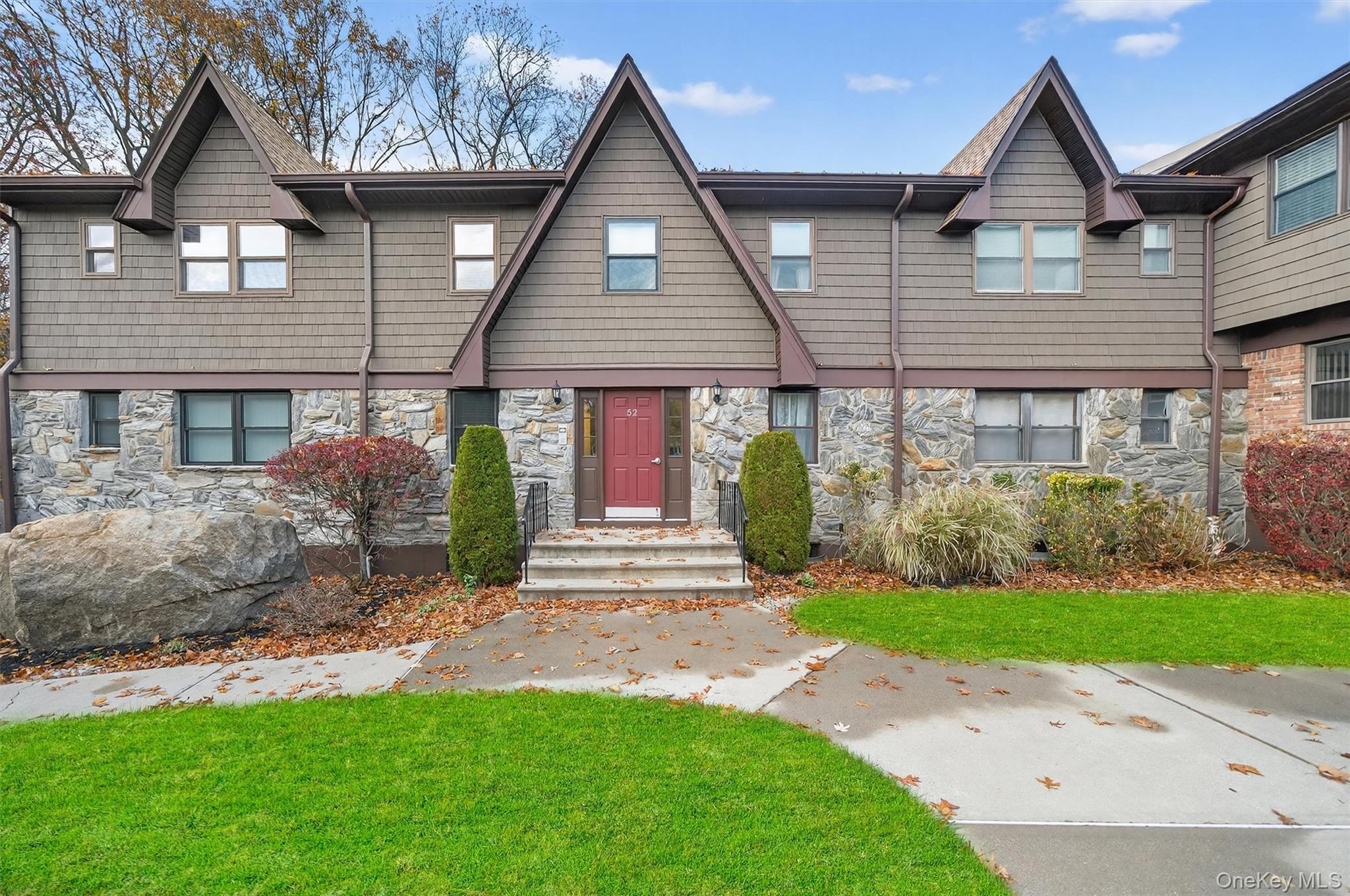 View of front of home with stone siding and a front yard