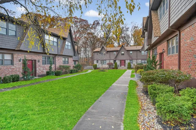 a view of a brick house with a yard and plants