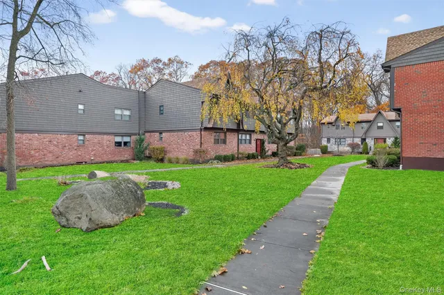 a view of a house with a big yard potted plants and large tree