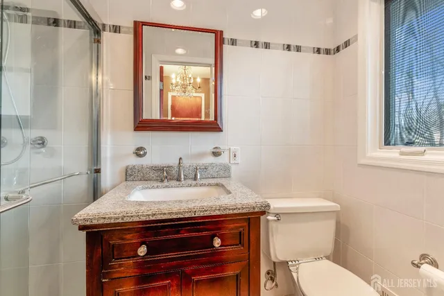 a bathroom with a granite countertop sink a mirror and shower