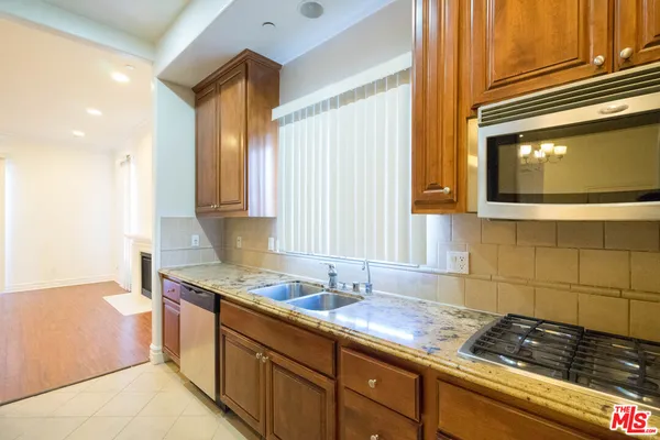 a kitchen with granite countertop a sink a stove and cabinets