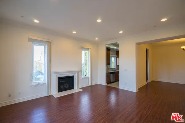 a view of an empty room with wooden floor and a fireplace