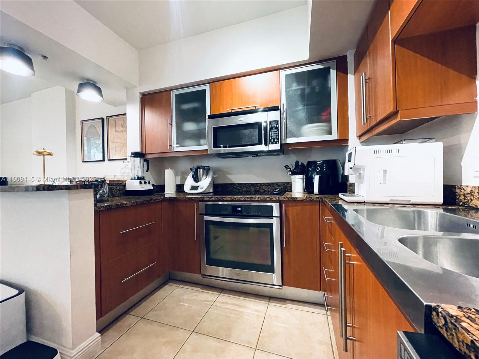 888 Douglas Road, Unit 119 Coral Gables, FL 33134 - Photo 6 of 36 a kitchen with stainless steel appliances granite countertop a stove a sink and a microwave