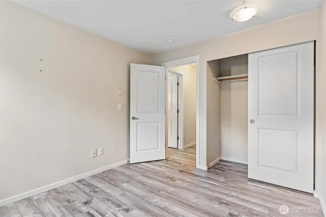 a view of an empty room with wooden floor and closet