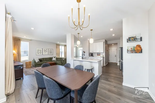 a view of a dining room and livingroom with furniture wooden floor a chandelier