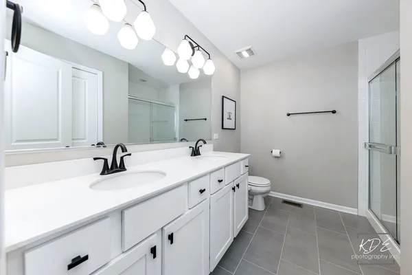 a bathroom with a double vanity sink mirror and toilet