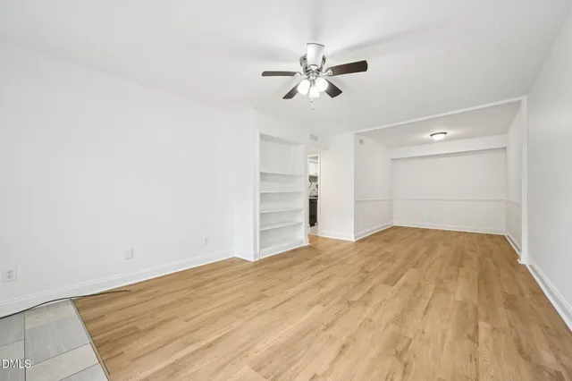 a view of empty room with wooden floor and fan