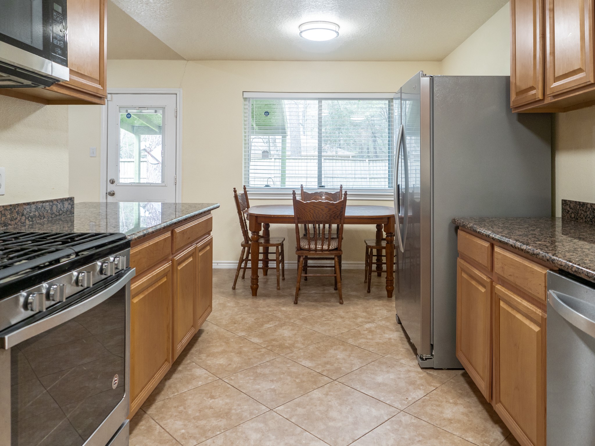 3302 Willie Way Spring, TX 77380 - Photo 4 of 25 a kitchen with stainless steel appliances granite countertop a stove top oven a sink dishwasher a dining table and chairs with wooden floor