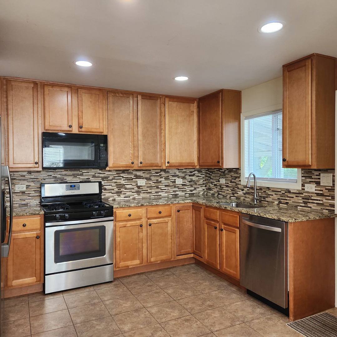 208 Albert Terrace Wheeling, IL 60090 - Photo 4 of 15 a kitchen with stainless steel appliances granite countertop wooden cabinets a stove a sink and a refrigerator