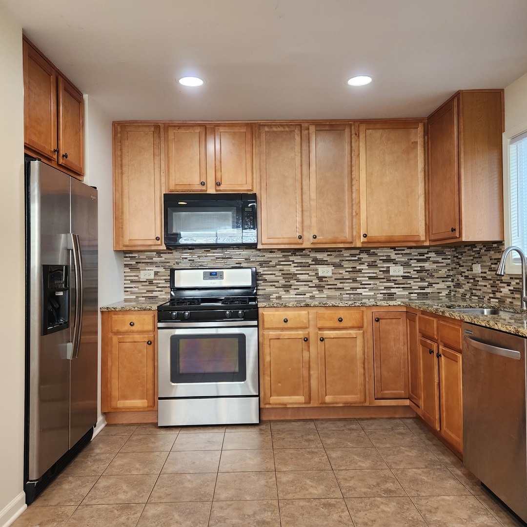 208 Albert Terrace Wheeling, IL 60090 - Photo 5 of 15 a kitchen with granite countertop stainless steel appliances a stove a sink and a refrigerator
