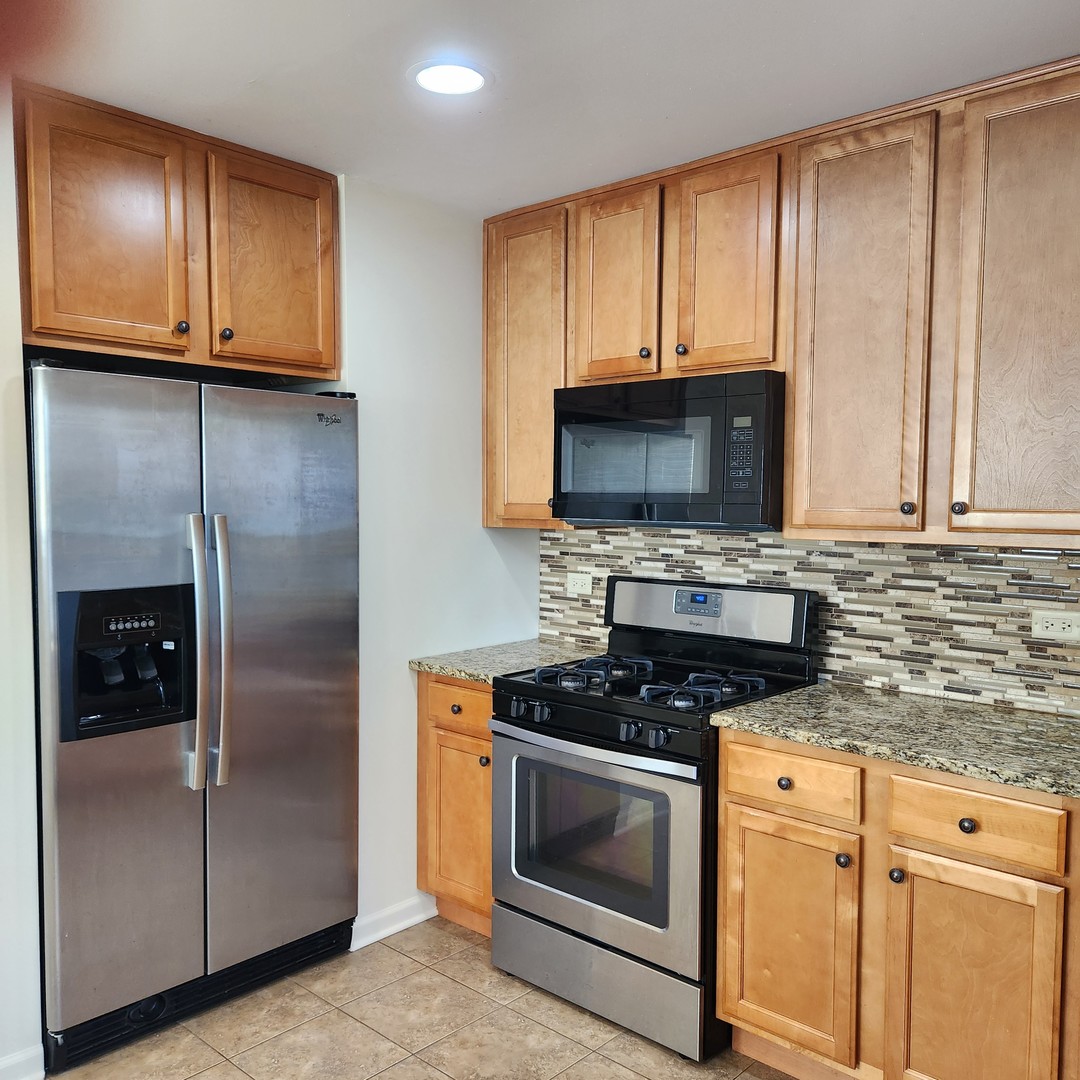 208 Albert Terrace Wheeling, IL 60090 - Photo 6 of 15 a kitchen with granite countertop a refrigerator stove and microwave